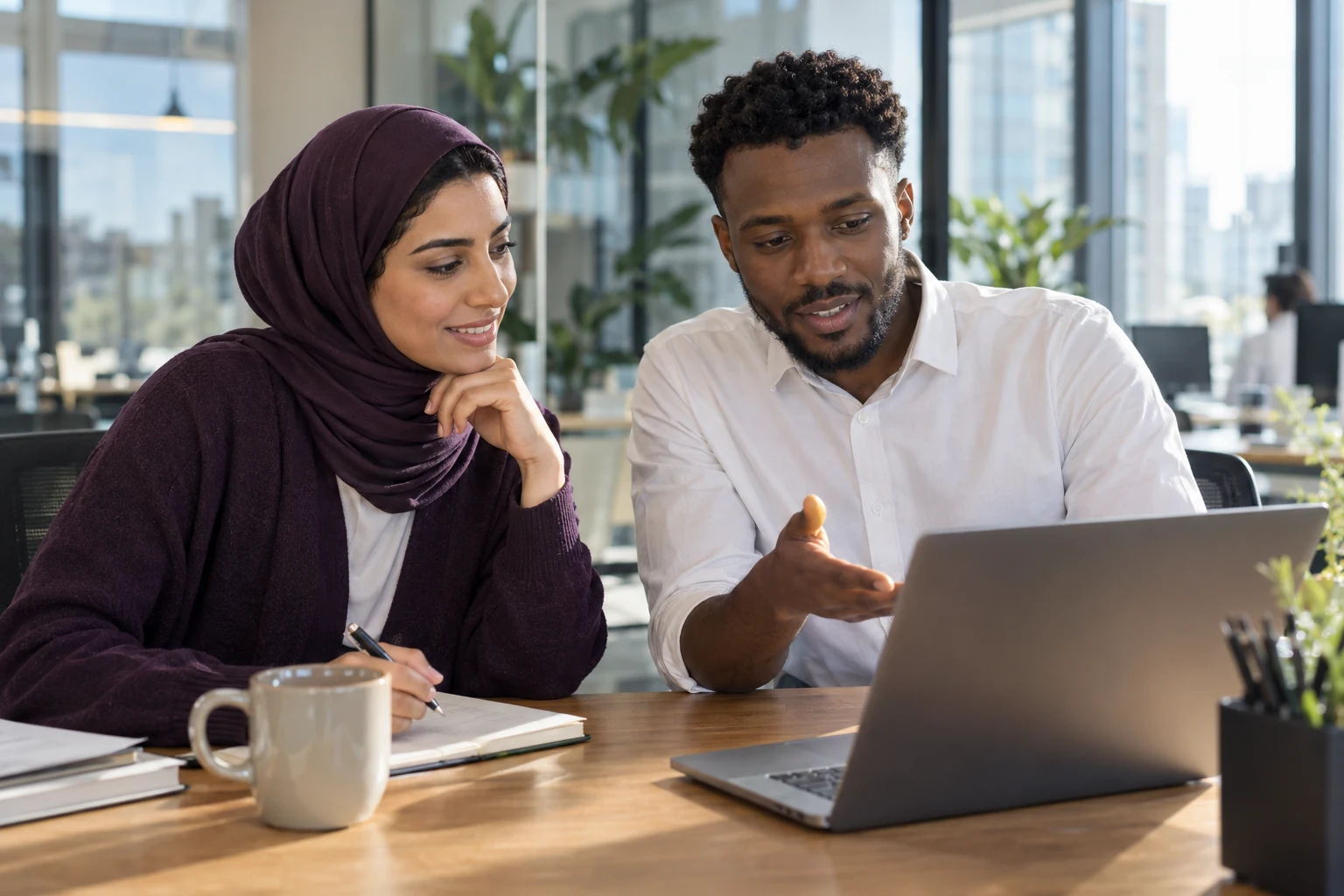 Two employees working through a project together at a laptop